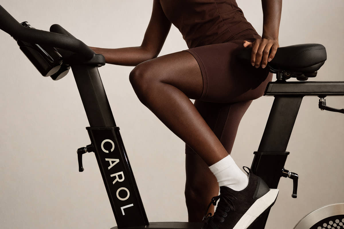 A rider pedaling a CAROL Bike, shown from the side